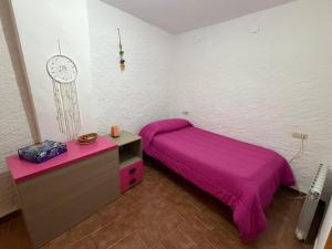 a bedroom with a purple bed and a clock on the wall at Casa Rural La Abejuela in Abejuela +2 photos