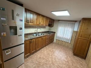 a kitchen with wooden cabinets and a stainless steel refrigerator at Casa Rural La Abejuela in Abejuela
