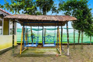 a gazebo with blue chairs and a straw roof at Super Hotel O Chilapata Forest Formerly Moner Manush Homestay in Uttar Simlabari