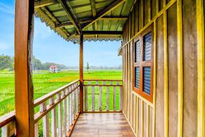 a balcony of a house with a view of a rice field at Super Hotel O Chilapata Forest Formerly Moner Manush Homestay in Uttar Simlabari