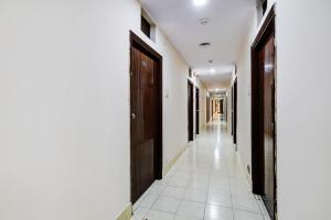 a hallway with wooden doors and a white tile floor at Hotel O Paradise Circle in Hyderabad