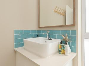 a bathroom with a white sink and blue tiles at Alwil Apartment 11 in Struisbaai +8 photos