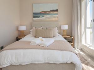 a bedroom with a large white bed with two lamps at Alwil Apartment 11 in Struisbaai