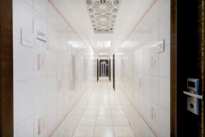 a hallway with white tile walls and a ceiling at Collection O Chidambaram Stadium Formerly Hotel Admire Suit in Chennai