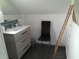 a bathroom with a sink and a black chair at Au château d'eau in Quintin