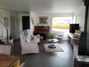a living room with a couch and a piano at Au château d'eau in Quintin