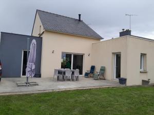 a house with a patio with a table and chairs at Au château d'eau in Quintin