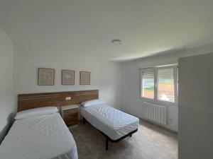 a bedroom with two beds and a desk and a window at Apartamentos Vive Laxe in Laxe