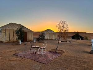 two chairs and a table in front of tents in the desert at Sahara Standard Camp in Merzouga