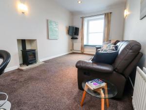 a living room with a leather couch and a fireplace at Flat 2, Dorstan in Carnforth