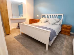 a bedroom with a white bed and a blue wall at Flat 2, Dorstan in Carnforth