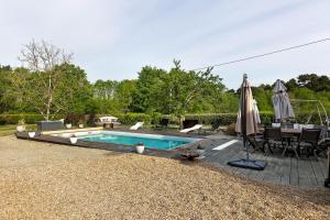 a swimming pool with a table and an umbrella at La Lizardiere des Landes in La Flèche