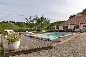 a wooden deck with a swimming pool and a house at La Lizardiere des Landes in La Flèche