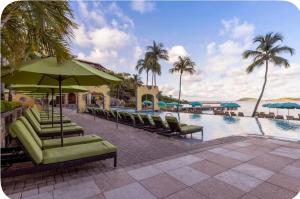 a pool with chairs and umbrellas next to the ocean at Saint Thomas Villa with Ocean view in Frenchmans Reef Heliport