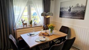 a dining room table with chairs and a table with flowers on it at LandHaus Hof Wehlenbach in Hallenberg