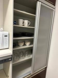 a refrigerator with cups and dishes in it at Hanako-Home in Fukuoka