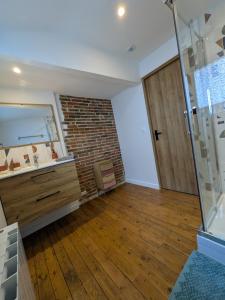 a bathroom with a brick wall and a wooden floor at Laroseliere in Mauléon