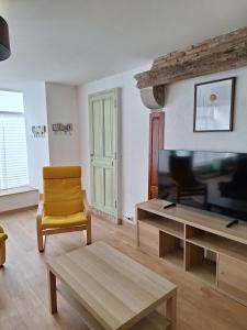 a living room with a tv and a yellow chair at Laroseliere in Mauléon
