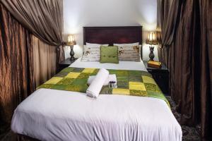 a bedroom with a large bed with green and yellow sheets at Zoete Rust Guesthouses in Lephalale