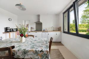 a kitchen with a table with a vase of flowers on it at Gite Les 3 Tilleuls in La Ville Dieu du  Temple +20 photos