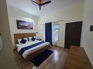 a bedroom with a bed with blue and white pillows at Hotel Aashirwad in Chamoli