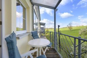 a balcony with a table and chairs and a window at Apartment mit Gartenblick K1 201 in Spalt