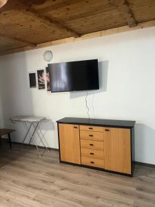 a flat screen tv on a wall with a wooden cabinet at Orchidea Apartman in Bačka Topola