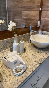 a hair dryer on a counter next to a sink at Cobertura Duplex 301 espaçoso e com vista para as montanhas in São Lourenço +31 photos
