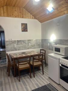 a kitchen with a table and chairs and a microwave at Orchidea Apartman in Bačka Topola