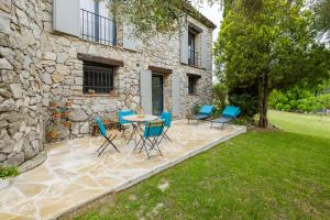 a patio with chairs and a table in front of a stone building at Villa Cyprès Bleu in Peymeinade