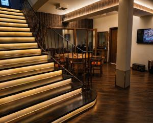 a lobby with a staircase with a table and a dining room at Makadam Hotel in Prizren