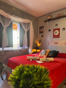 a bedroom with a bed with red sheets and a window at Suíte Harry Potter - Pousada Castelo do Luar in Penha