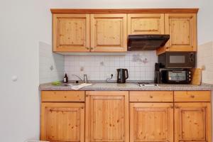 a kitchen with wooden cabinets and a sink and a microwave at Superior Apt mit Seeblick K2 102 in Spalt