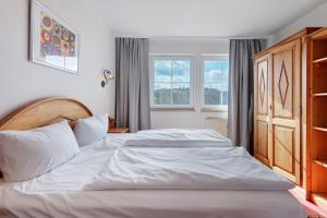 a bedroom with a large white bed and two windows at Superior Apt mit Seeblick K2 102 in Spalt