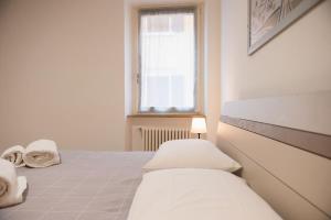 a white bedroom with two beds and a window at Diamante Luxury Apartment in Torri del Benaco