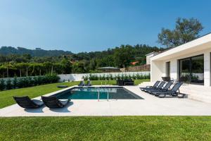 a backyard with a swimming pool and chairs at Casinha da Ribeira in Vila Verde