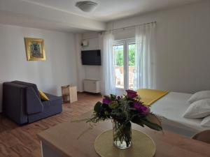 a room with a bed and a vase of flowers on a table at Apartments Ivanovski in Rab