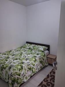 a bedroom with a bed with a green and white comforter at Modern 1-Bedroom Apartment with AC, Free Parking & Self Check-in Bucharest-Militari in Dudu
