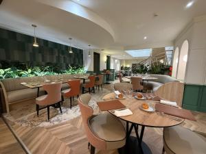 a restaurant with tables and chairs and plants at Logis Hotel Restaurant La Marjolaine in Moulay