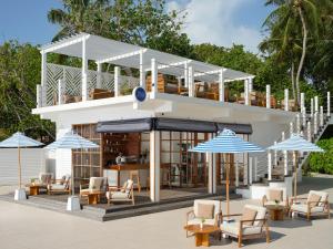 a building with tables and chairs and umbrellas at Villa Nautica Paradise Island Resort in Himmafushi