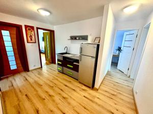 a kitchen with a refrigerator and a wooden floor at Zaciszny domek in Słupsk