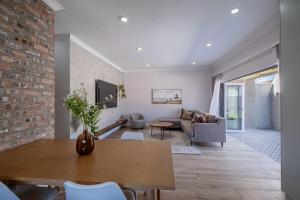a living room with a table and a brick wall at The Shirley Too in Gqeberha