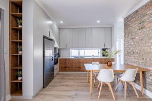 a kitchen with a table and chairs and a brick wall at The Shirley Too in Gqeberha