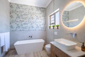 a bathroom with a tub and a sink and a mirror at The Shirley Too in Gqeberha +32 photos