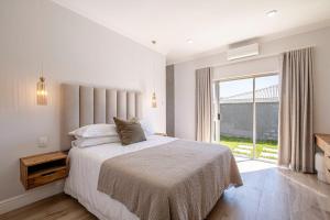 a bedroom with a bed and a large window at The Shirley Too in Gqeberha