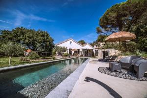 a pool with chairs and an umbrella next to a house at Domaine S&B in Aubenas