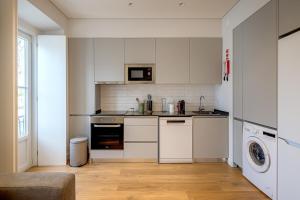 a kitchen with white cabinets and a washer and dryer at CapeTown Marula 1BR apartment in Caparica