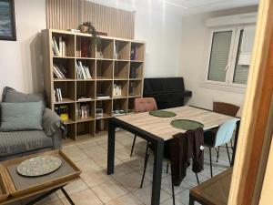 a living room with a table and a book shelf at APPARTEMENT CONLEAU VANNES avec JARDIN PARTAGE in Vannes