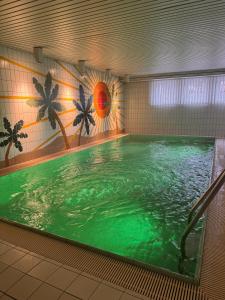 a swimming pool with green water in a building at Hotel Vierjahreszeiten in Breitengüßbach