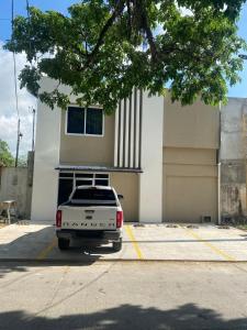 a white truck parked in a parking lot in front of a building at Hotel Merendón Express in San Pedro Sula